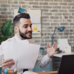 a man sitting at a desk with a laptop and papers