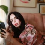 a woman laying on a couch looking at a cell phone