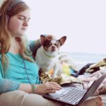 girl in blue jacket holding white and brown short coated puppy