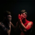 a couple of men covered in red paint