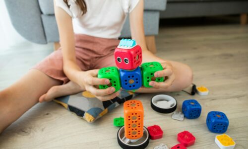 girl in white shirt playing with blue and red car toy