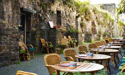 a row of tables and chairs sitting next to a stone wall