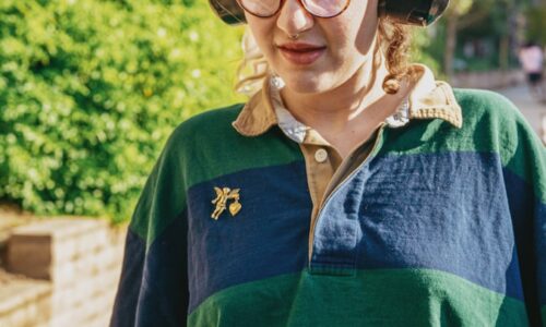 Portrait of a nonbinary autistic person outdoors using headphones