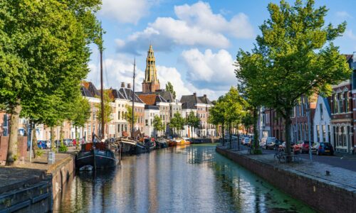 boat on river near green trees and buildings during daytime