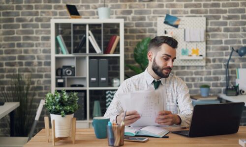 a man sitting at a desk with a laptop and papers