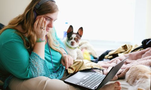 woman in teal long sleeve shirt holding black laptop computer