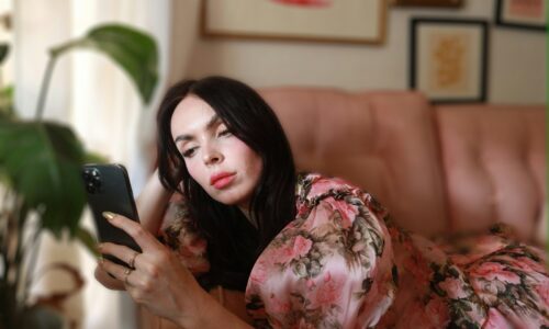 a woman laying on a couch looking at a cell phone