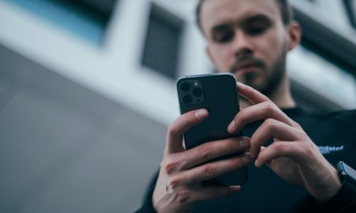 man wearing black sweater using smartphone