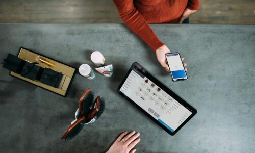 person holding smartphone beside tablet computer